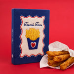 Blue clutch with 'French Fries' design next to a basket of fries on a red background